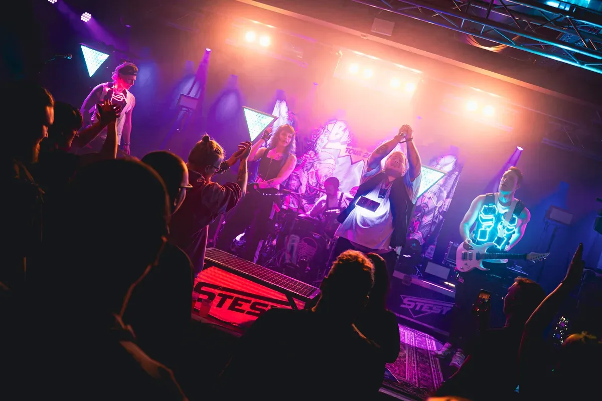 Volle Buehne mit Band und Publikum unter warmen Lichtern