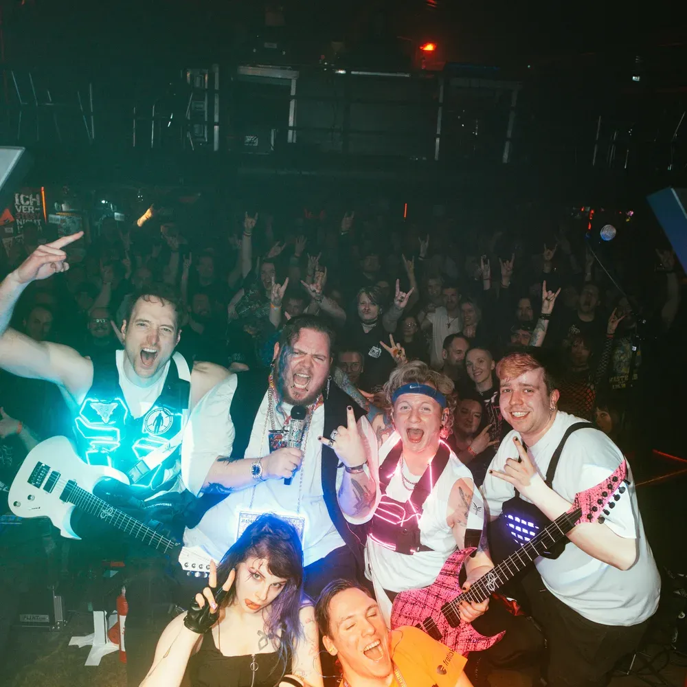 Gruppenfoto der ganzen Band mit Publikum im Hintergrund