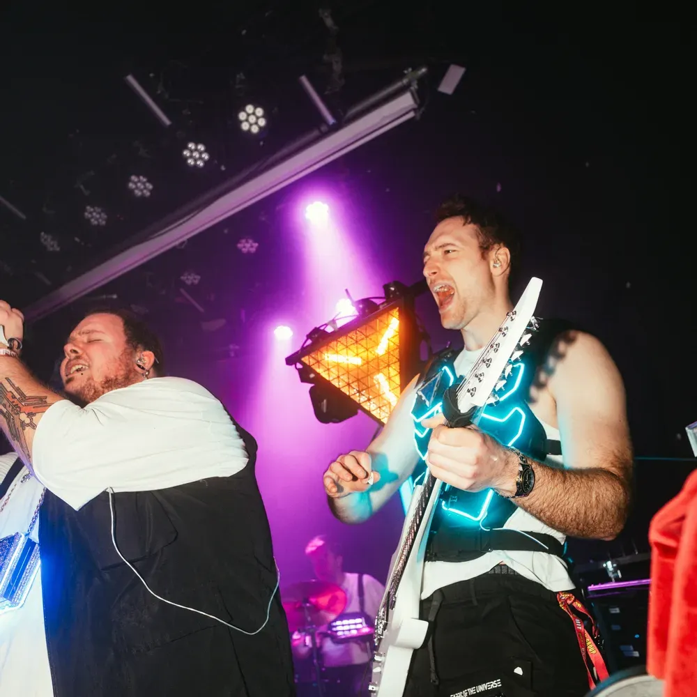 Saenger und Gitarrist geben alles unter violettem Nebel